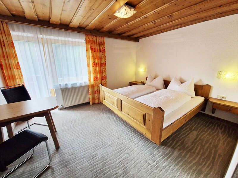 Room with double bed, seating area and balcony in Apartment 3