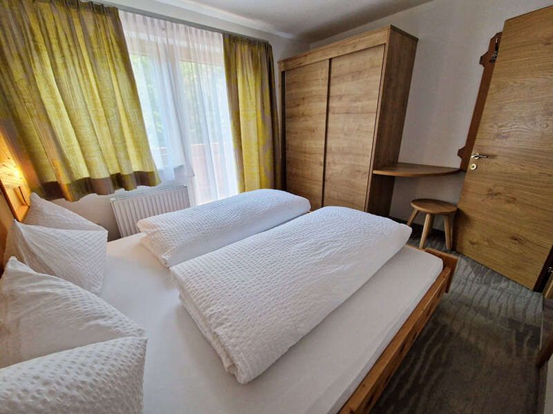 Room with double bed, wardrobe and small table with stool