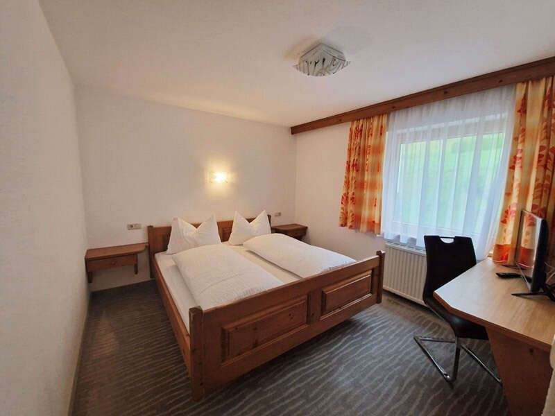 Double bed, table and television in the room in Apartment 3